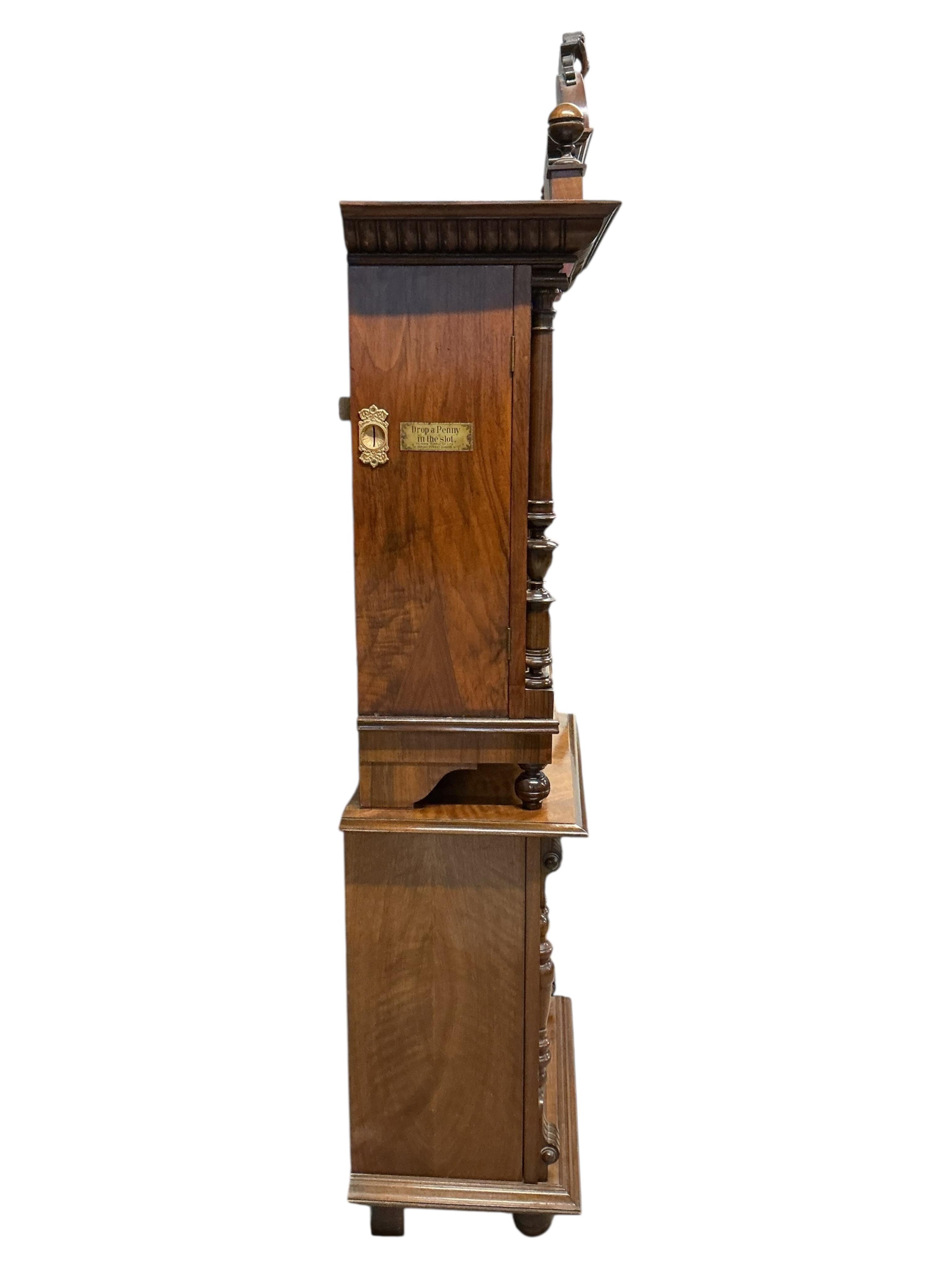 A floor standing coin-operated walnut polyphon disc player with nine 50cm diameter discs, the base containing storage compartments for the discs, coin slots on both sides with guilt finished surrounds next to applied lab